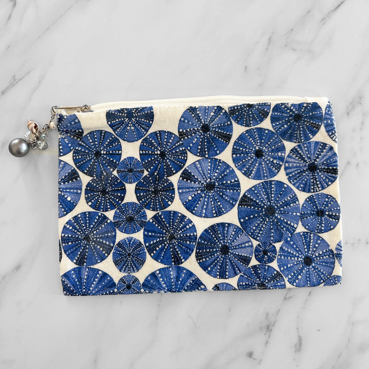 A canvas tote bag with blue and white urchin pattern and a zipper with charms.