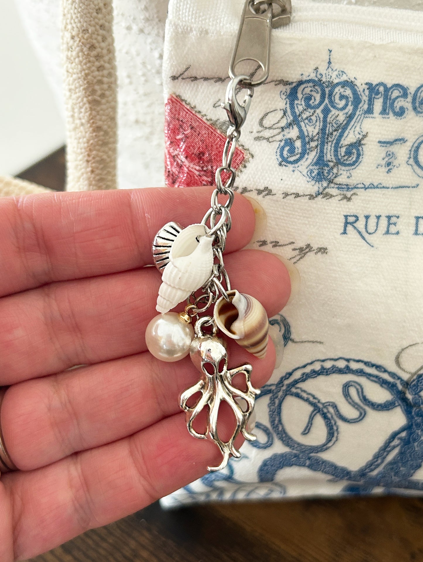 Charms on zipper featuring seashells, a silver octopus, and a pearl charm.