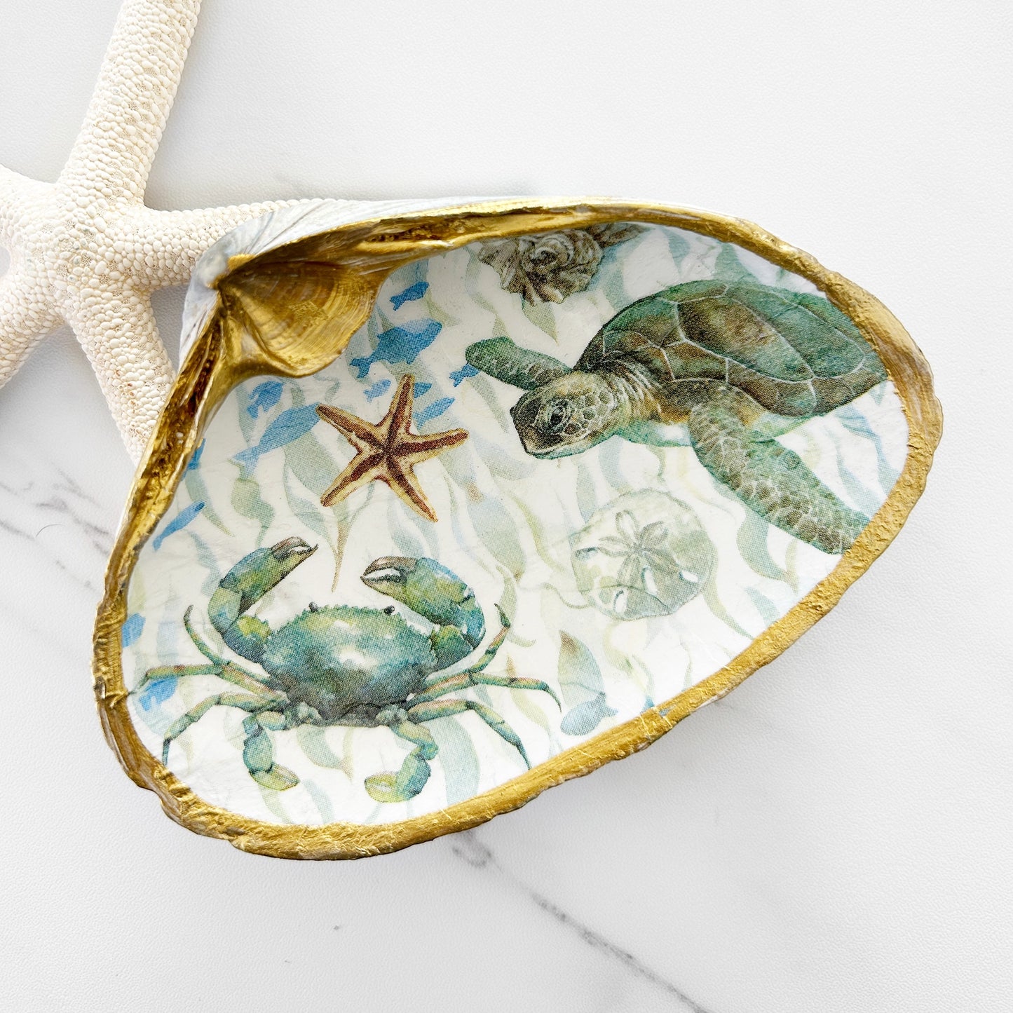 Decorative shell with sea-themed design featuring a turtle and crab on a white background