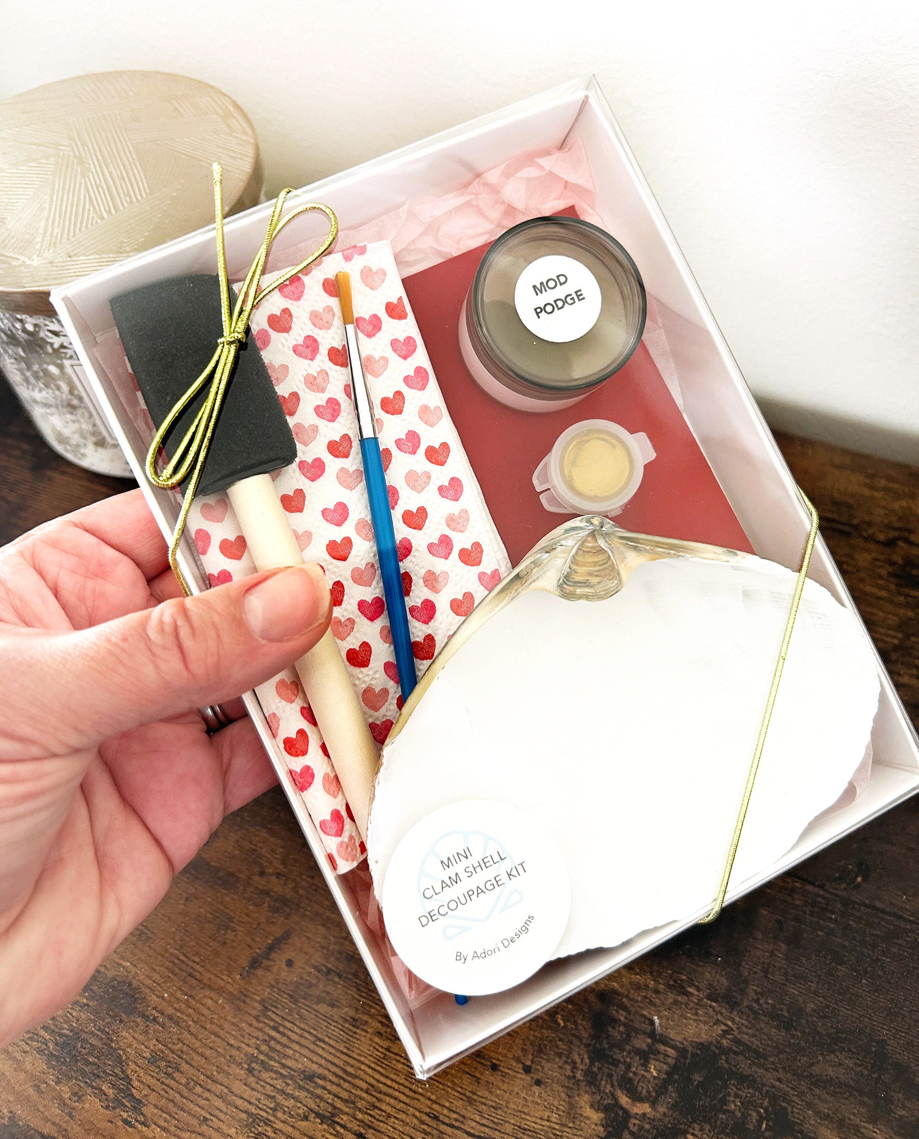 Decoupage kit with seashells and craft supplies and materials in a box on a wooden surface